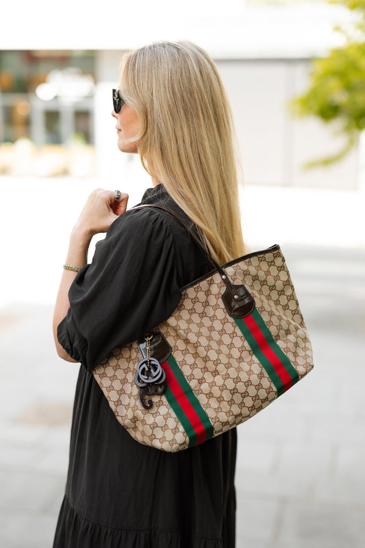Kvinne i sort kjole med vintage Gucci GG canvas tote med grønt og rødt web-bånd over skulderen