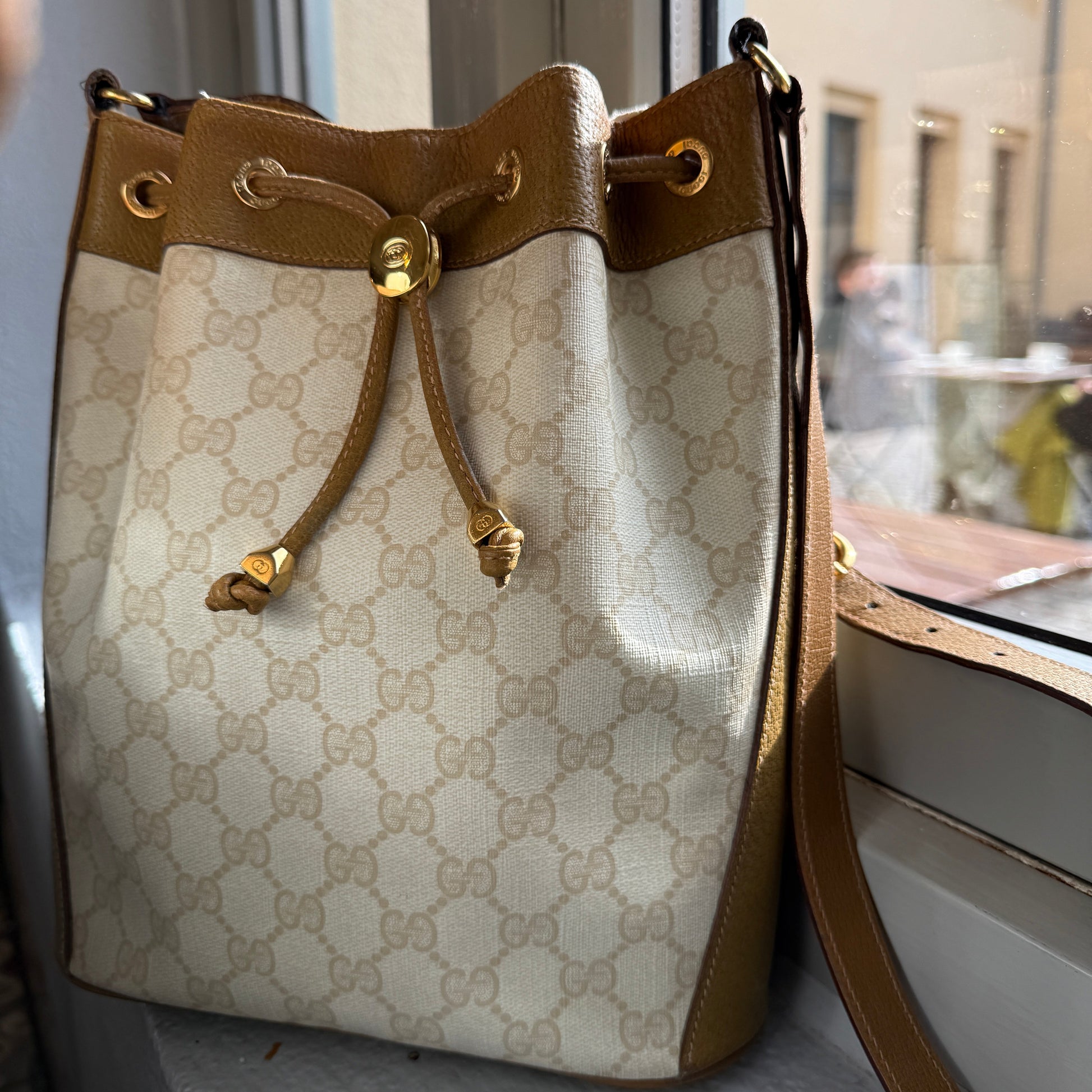 Designer handbag with beige and brown pattern on a reflective surface